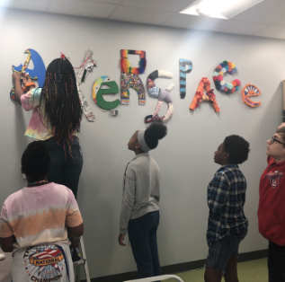  3D Design & Modeling students hanging the Makerspace sign they created.  